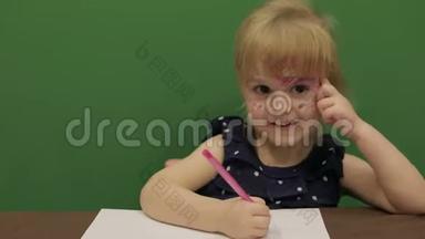 女孩在桌子边画画。 教育进程。 那个女孩有个好主意。 快乐的三岁女孩。 可爱的女孩微笑
